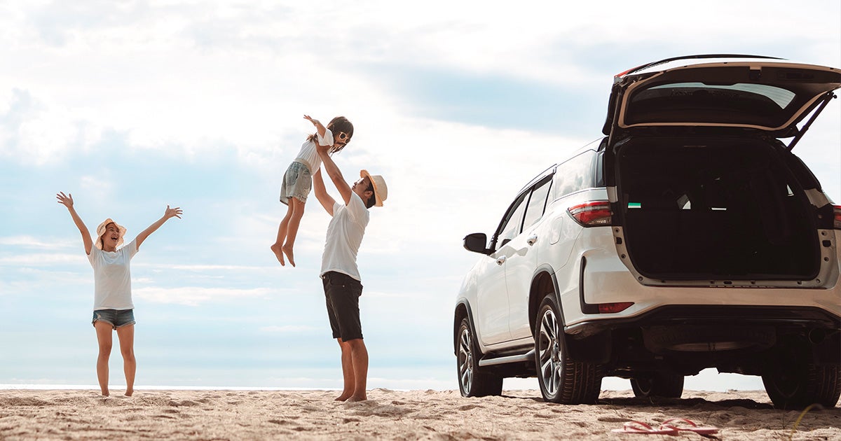 A family on the beach by their white SUV