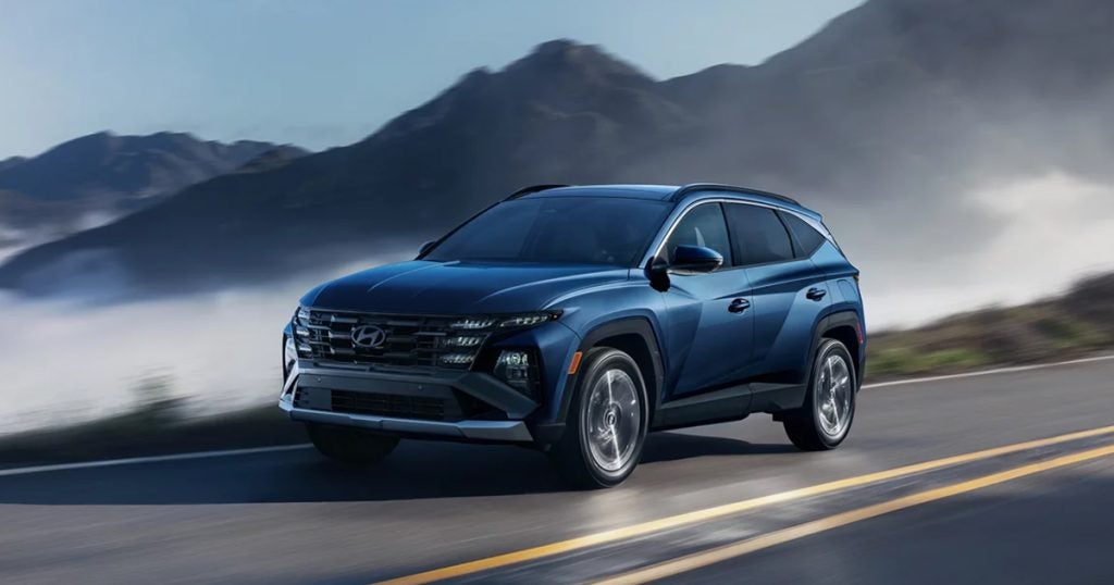 The 2025 Hyundai Tucson driving on a road through the mountains.