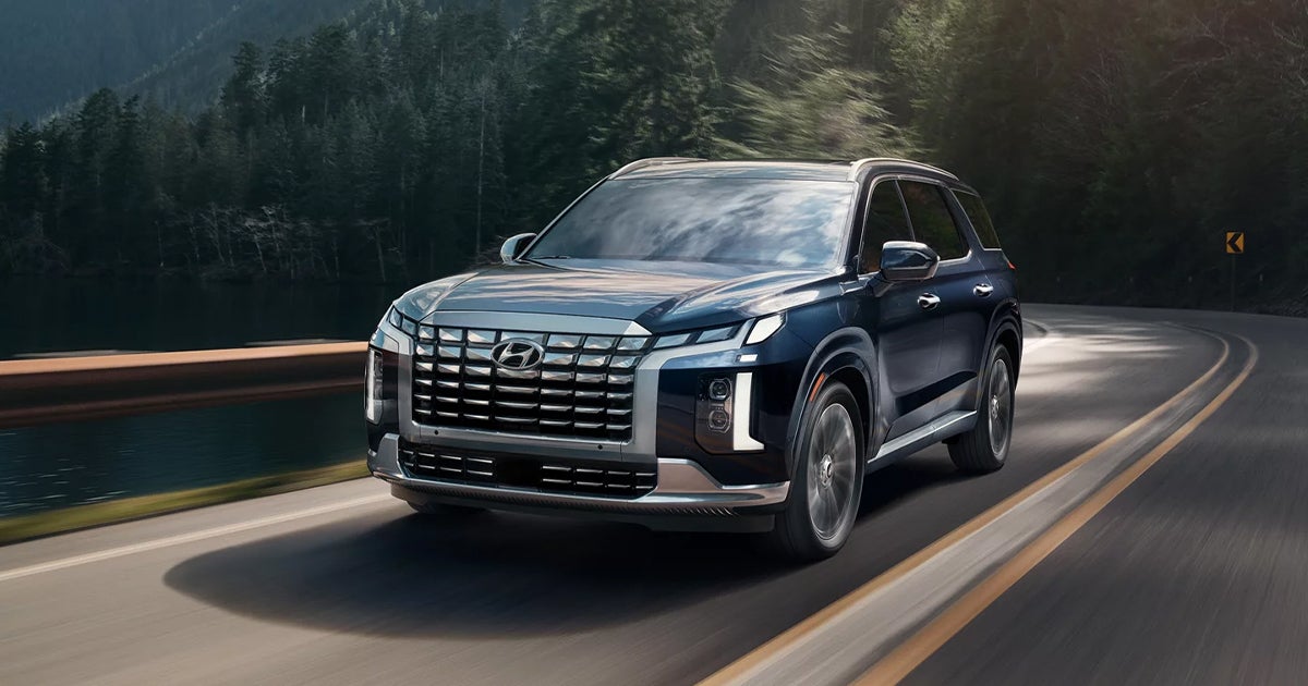 A Hyundai Palisade driving on the road.