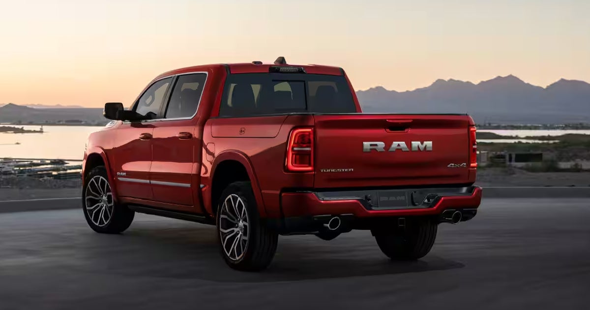 A RAM 1500 Tungsten pickup truck in a red exterior color parked by a lake.
