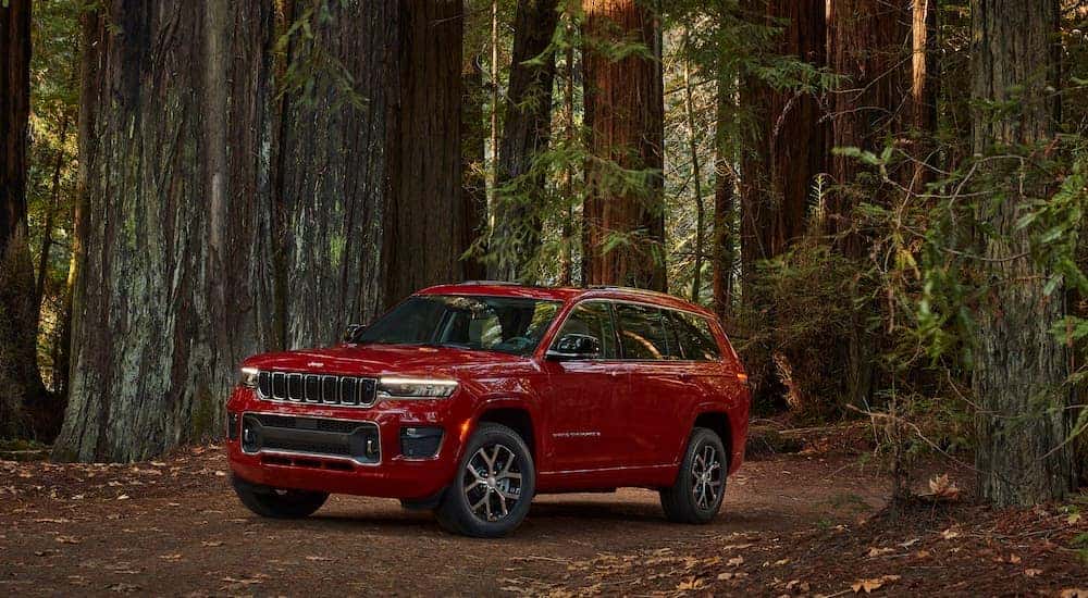 A red 2022 Jeep Grand Cherokee L Overland is shown parked in a woodsy area.