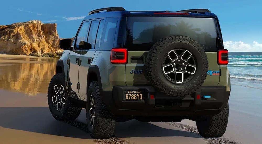 A 2024 Jeep Recon 4xe is shown from the rear on a beach after leaving a dealer that sells all-electric Jeep vehicles.