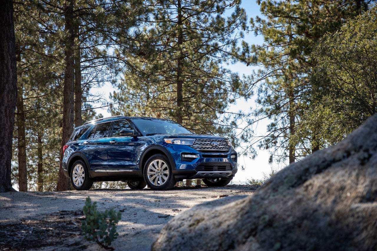 A blue 2020 Ford Explorer Limited parked on a rock in a forest