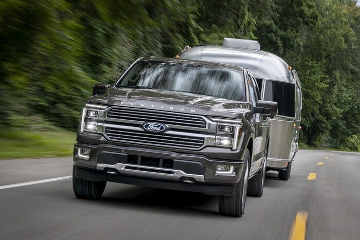 Gray Ford F-150 towing a trailer and driving on the road