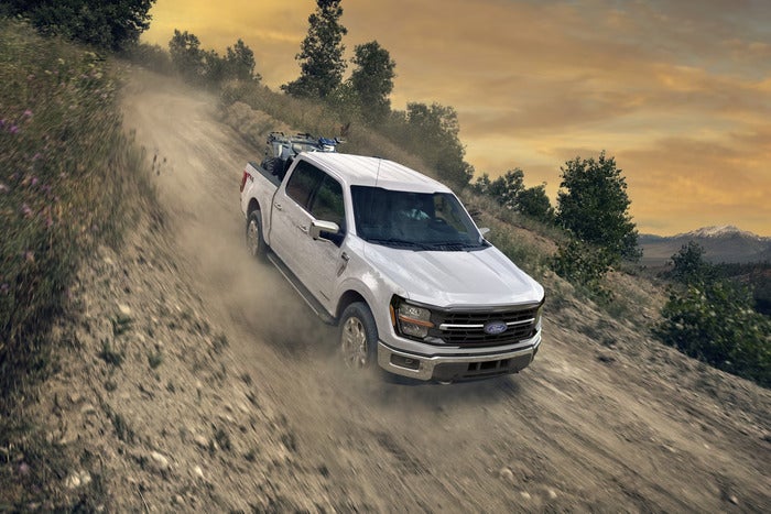 White Ford F-150 driving down a hill