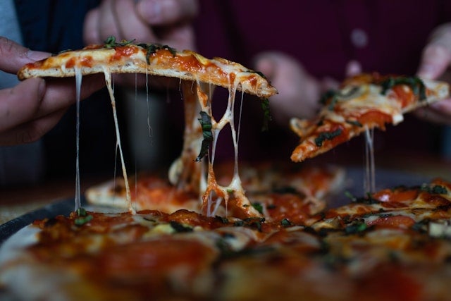 Person picking sliced pizza