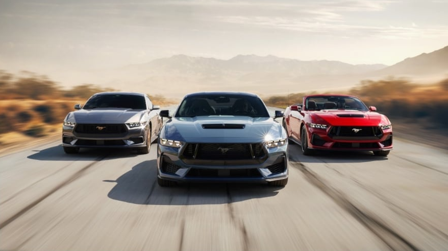 Three Ford Mustangs driving down road