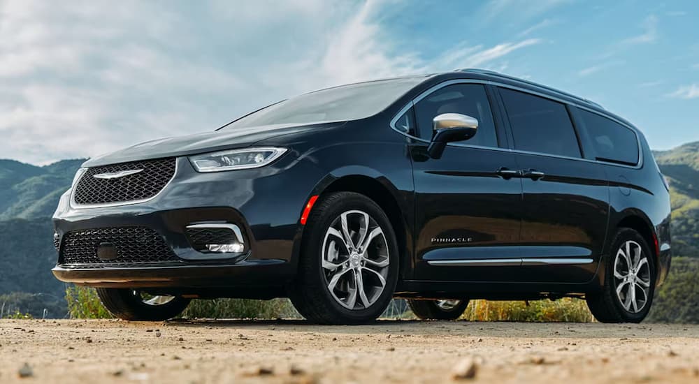 Low angle view of a black 2024 Chrysler Pacifica Pinnacle in front of mountains.