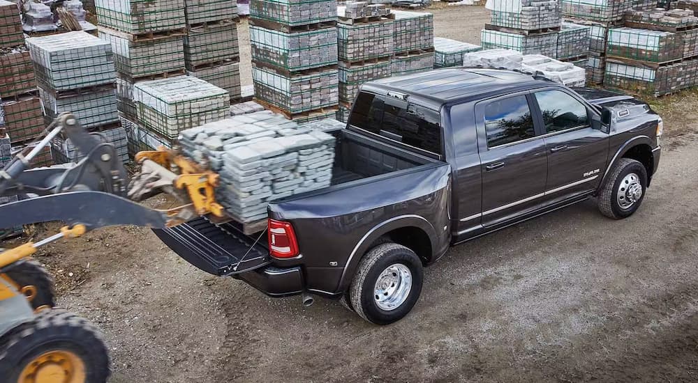 Overhead view of a tractor lowering a pallet of stone into the bed of a grey 2024 Ram 3500.