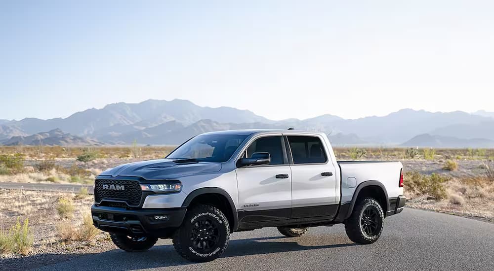 A white 2025 Ram 1500 Rebel parked on an empty road in the prairie.