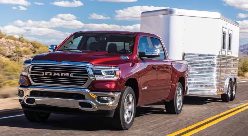 A red 2024 Ram 1500 Laramie towing a trailer.