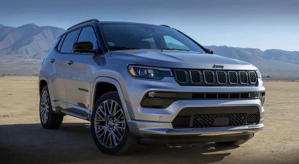 A silver used 2023 Jeep Compass for sale is parked off-road.