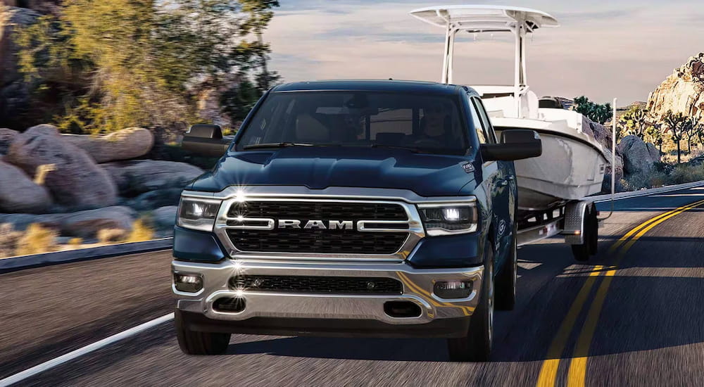 Front view of a blue 2024 Ram 1500 towing a boat.