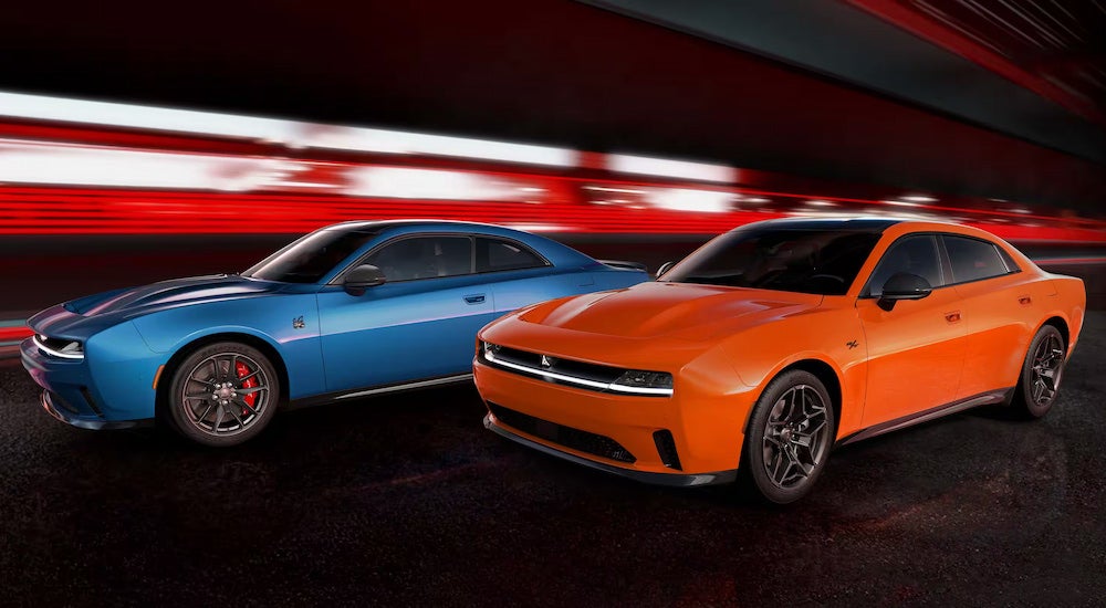 A blue 2025 Dodge Charger Daytona Scat Pack parked next to an orange 2025 Dodge Charger Daytona RT.