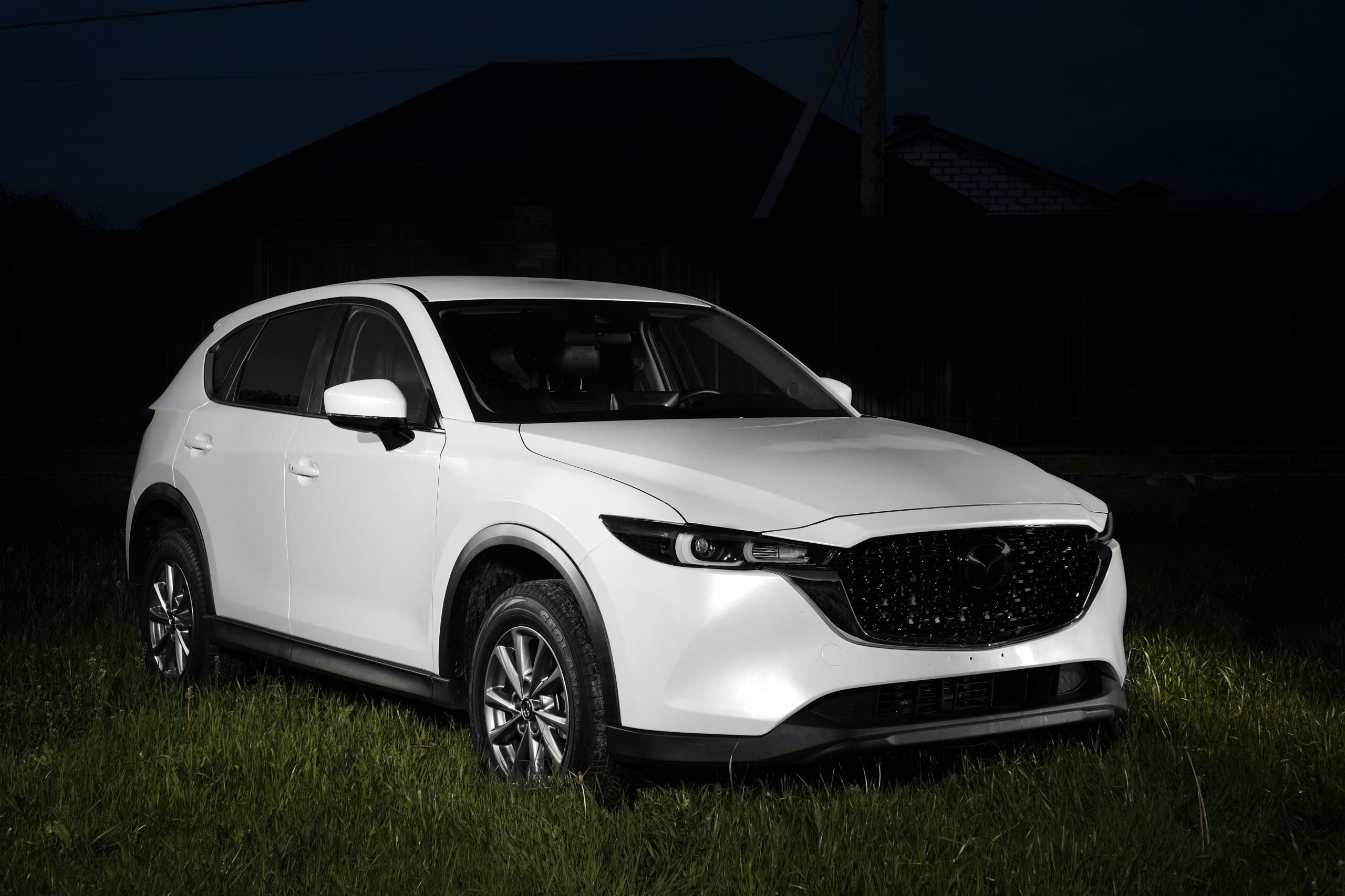 a white mazda cx - 5 parked in a field at night