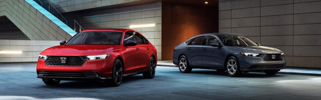 2025 Honda Accord lineup in red and gray parked outside a modern building, showcasing the sleek exterior design and premium styling of Honda’s midsize sedan in Indianapolis, IN.