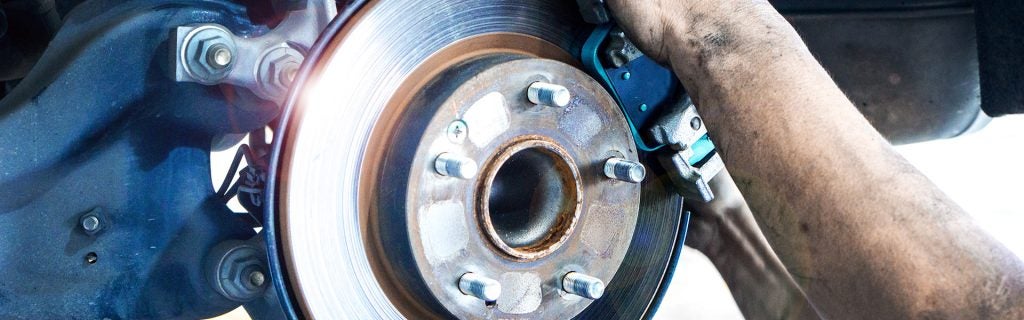 A close-up of a mechanic working on a vehicle's brake system.