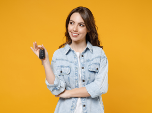 A person holding a set of car keys in front of a yellow background near Indianapolis, Indiana