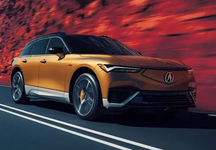 A gold-colored 2024 Acura ZDX driving down a road near Indianapolis, Indiana.