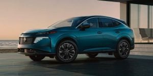Teal Nissan Murano SUV parked by a modern waterfront.