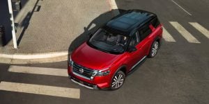 2025 Nissan Pathfinder in red driving through city streets in Indianapolis, IN, highlighting the SUV’s bold exterior design, spacious cabin, and modern performance features.
