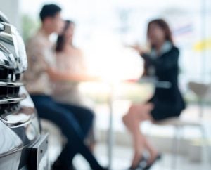 Two people talking to a sales agent at a Nissan dealership near Indianapolis, Indiana