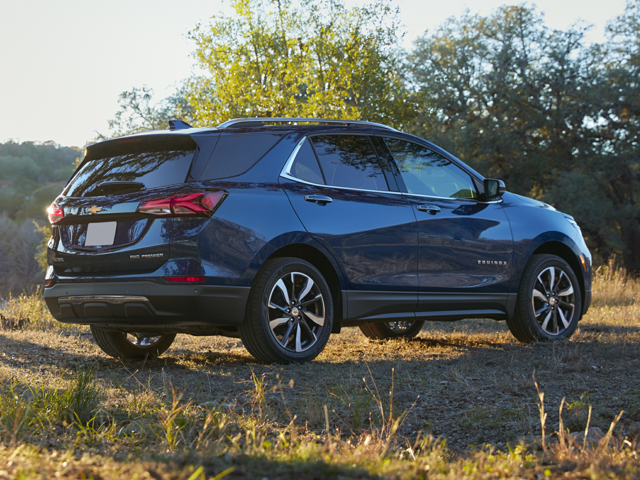 A Chevy Equinox parked outside in the grass near some trees
