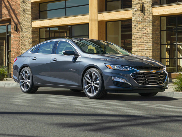 A silver Chevy Malibu parked next to a building