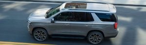 2026 Chevrolet Tahoe driving on a city road with a sleek exterior design.