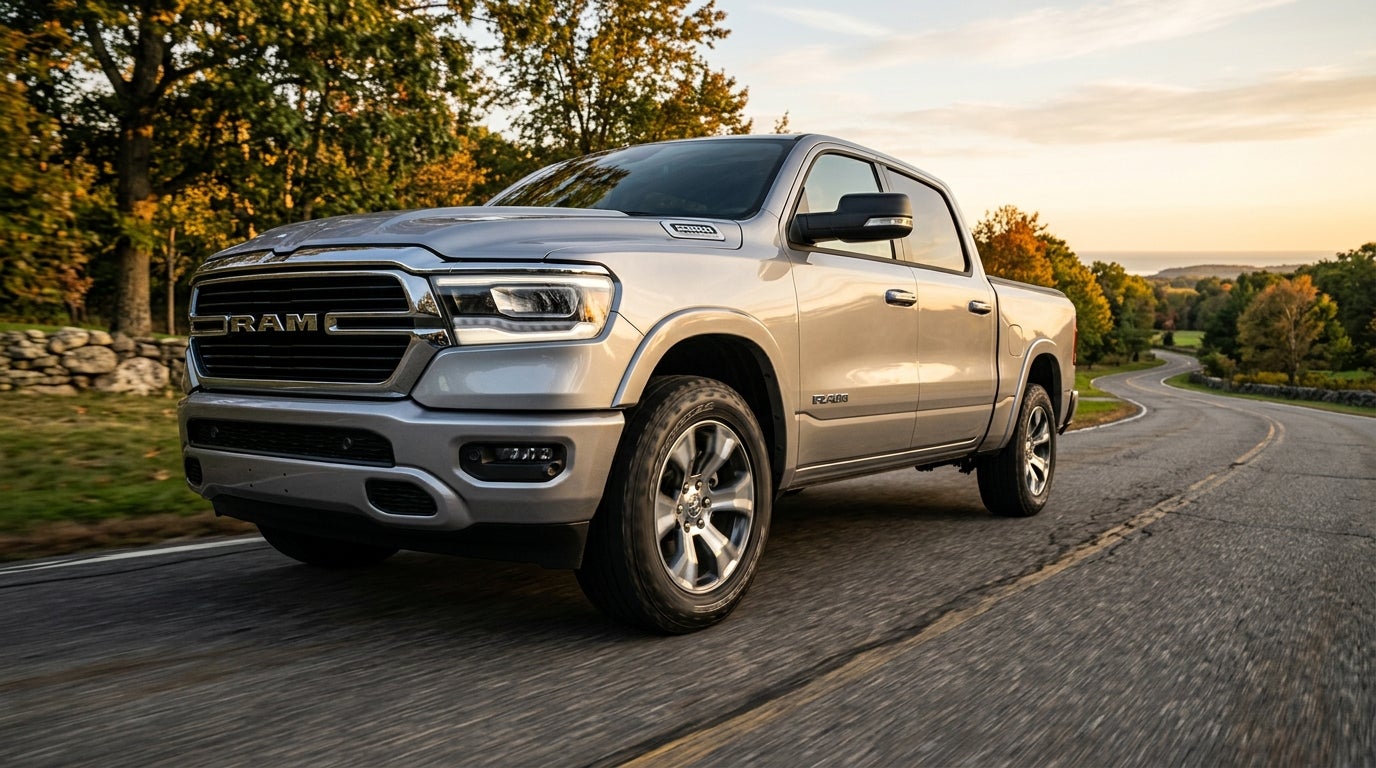 AI generated: Low-angle commercial automotive photography of a sleek silver Ram 1500 pickup truck cruising along a winding asphalt road, focus on the rugged all-season tires with deep tread patterns and polished alloy wheels, dynamic three-quarter view emphasizing the vehicle's powerful stance and precision alignment, golden hour sunlight casting warm glows and long shadows across the metallic body, lush suburban Northeast landscape with deciduous trees and soft coastal light in the background, sharp focus on the textured rubber meeting the road, subtle motion blur on the pavement to suggest smooth movement, high-contrast lighting, realistic textures, professional advertising style, clean and cinematic atmosphere, vibrant natural color palette.
