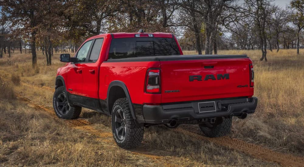 A red 2021 Ram 1500 driving through a field