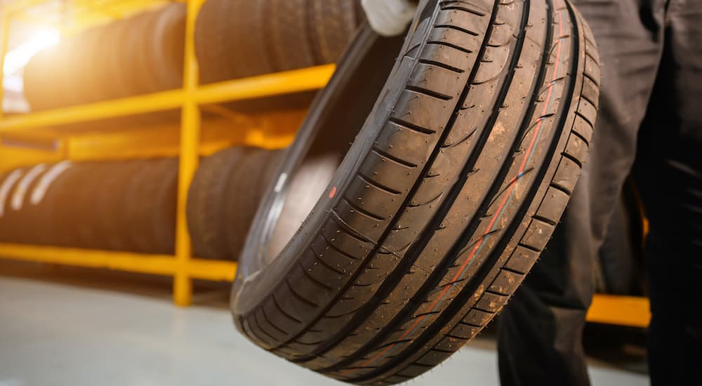 A mechanic is shown holding a tire at a tire rotation service center.