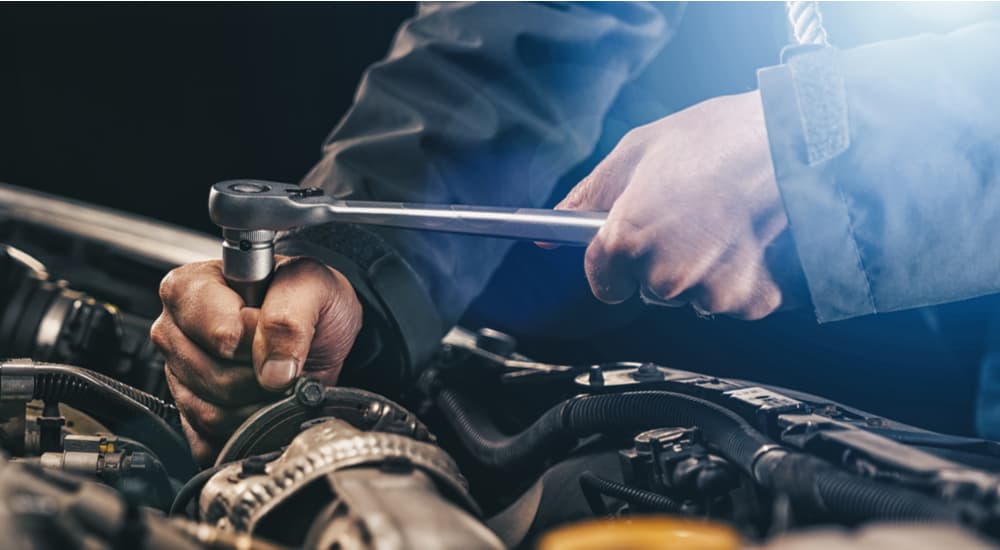 Close-up of a mechanic's hands while working on an engine at a certified pre-owned Ram dealer.