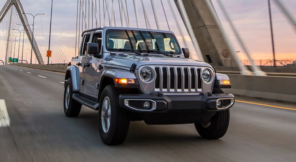 A silver 2021 Jeep Wrangler is shown from the front driving on a bridge after leaving a NJ Jeep Wrangler Dealer.