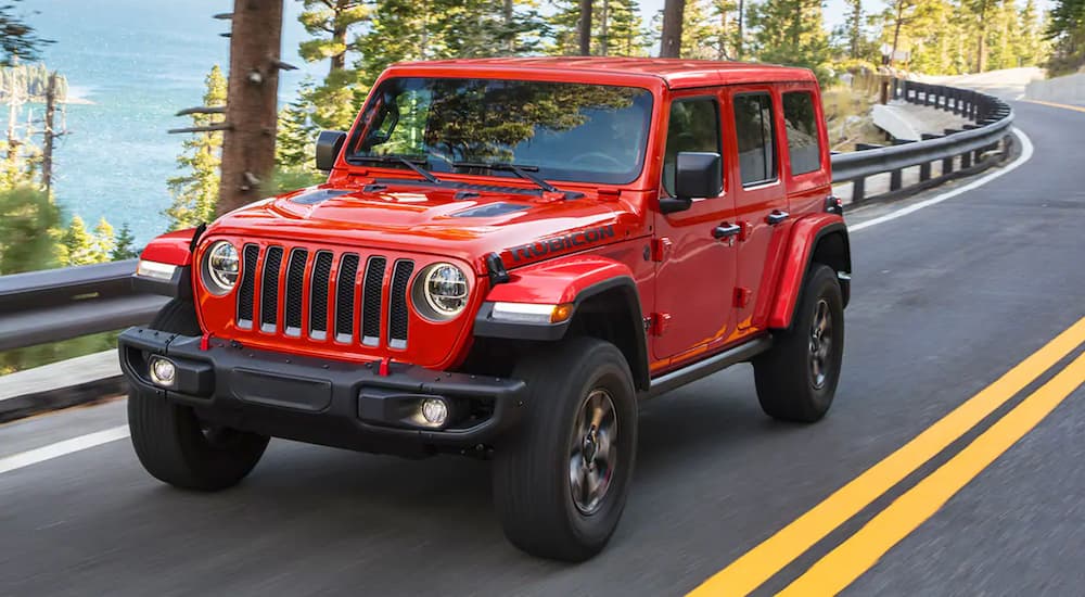 A red 2021 Jeep Wrangler driving on a windy road overlooking a valley