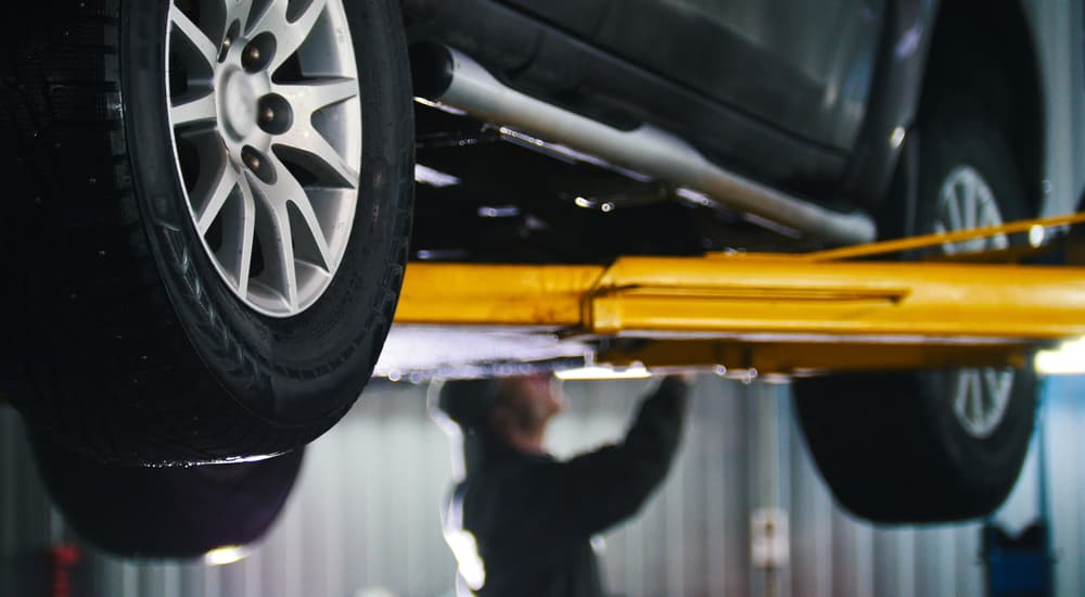 An SUV is shown on a lift while being worked on by a technician.