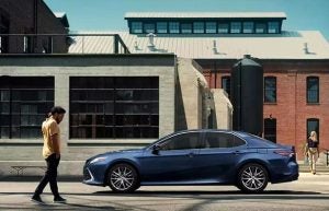 A person walking up to a blue 2023 Toyota Camry parked on a city street near Noblesville, Indiana