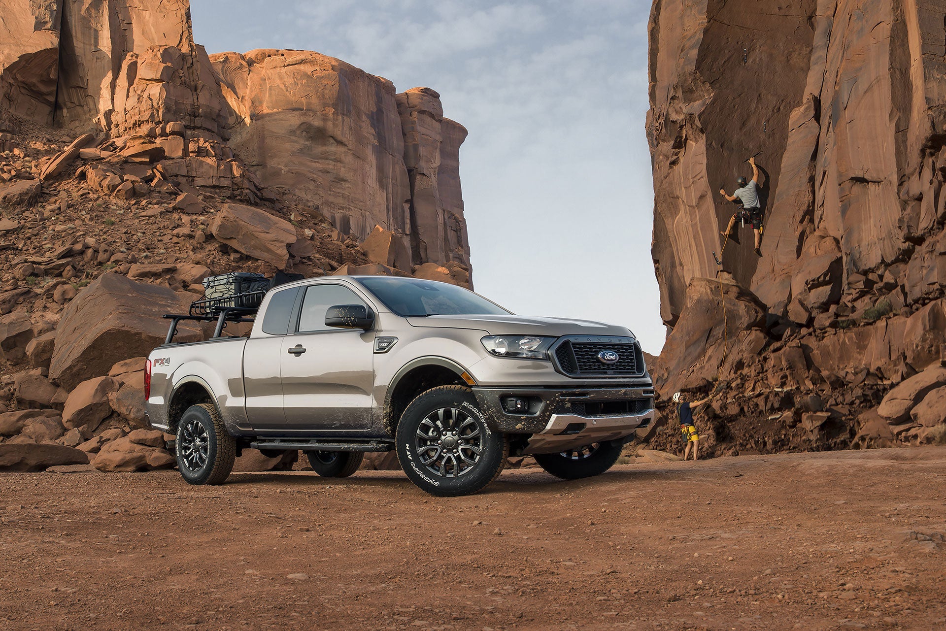 Ford Ranger parked around cliffs with man rockclimbing in the background
