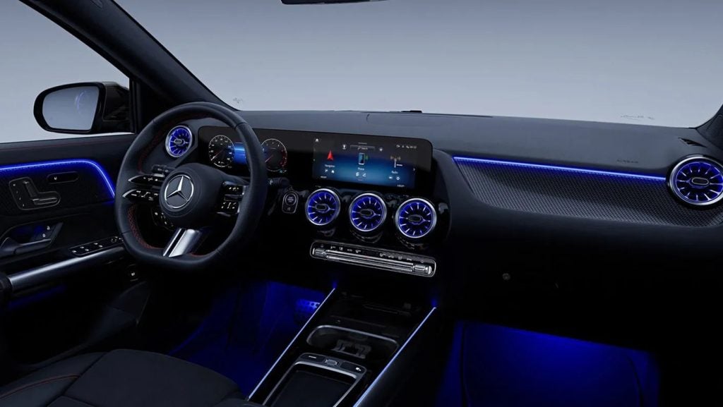 Interior cabin of the 2026 Mercedes-Benz GLC Hybrid showcasing digital displays, leather seating, and blue ambient lighting.