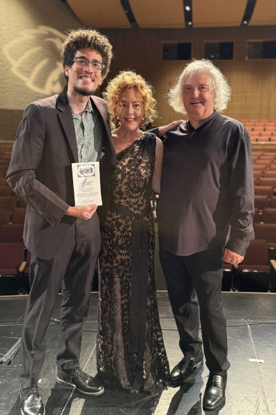 Three musicians posing on stage after a performance.