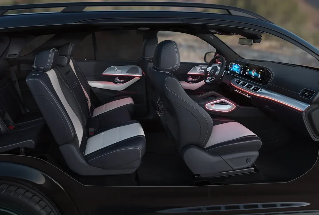 Side interior view of a Mercedes-Benz cabin with multiple rows of seats, ambient lighting, and modern displays designed for family comfort.