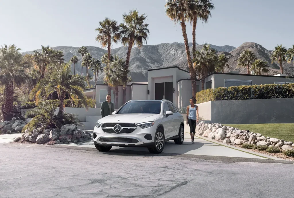 White 2026 Mercedes-Benz GLC parked outside a modern home with palm trees and mountains in the background, highlighting its upscale everyday appeal.
