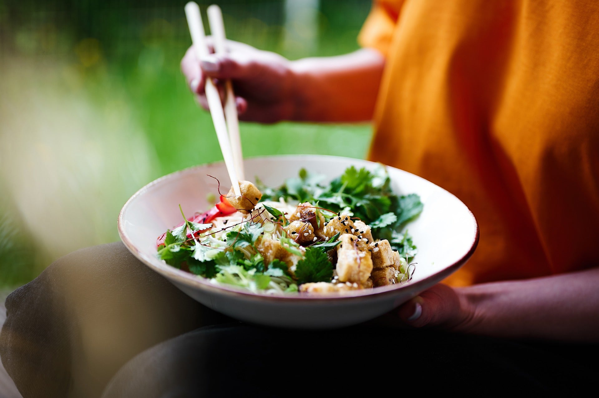 A person eating Asian food with chopsticks
