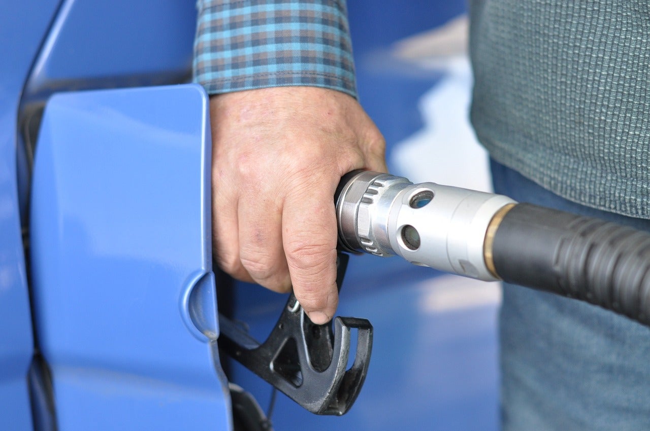 A man putting fuel in his light blu vehicle