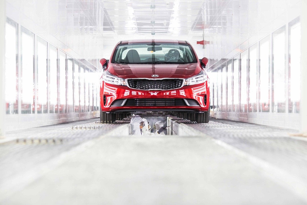 A person working on a red Kia vehicle in a factor