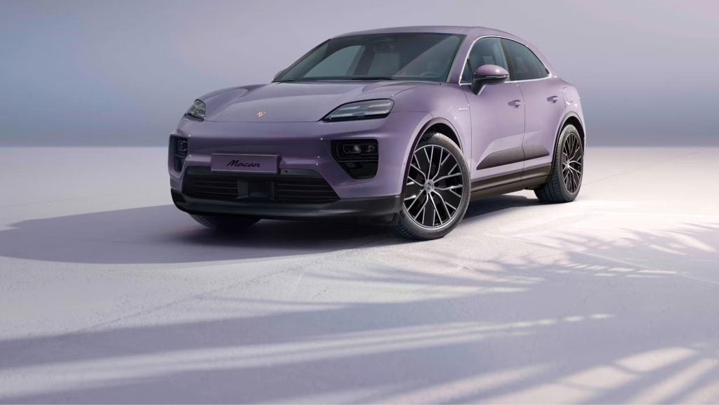Electric Porsche Macan charging at a station, symbolizing Porsche’s electric future.