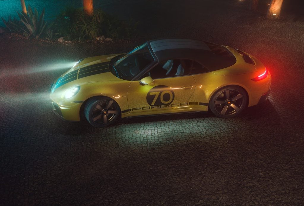 Overhead view of a gold 2026 Porsche 911 at night, highlighting the new hybrid performance system in Porsche’s legendary sports car.