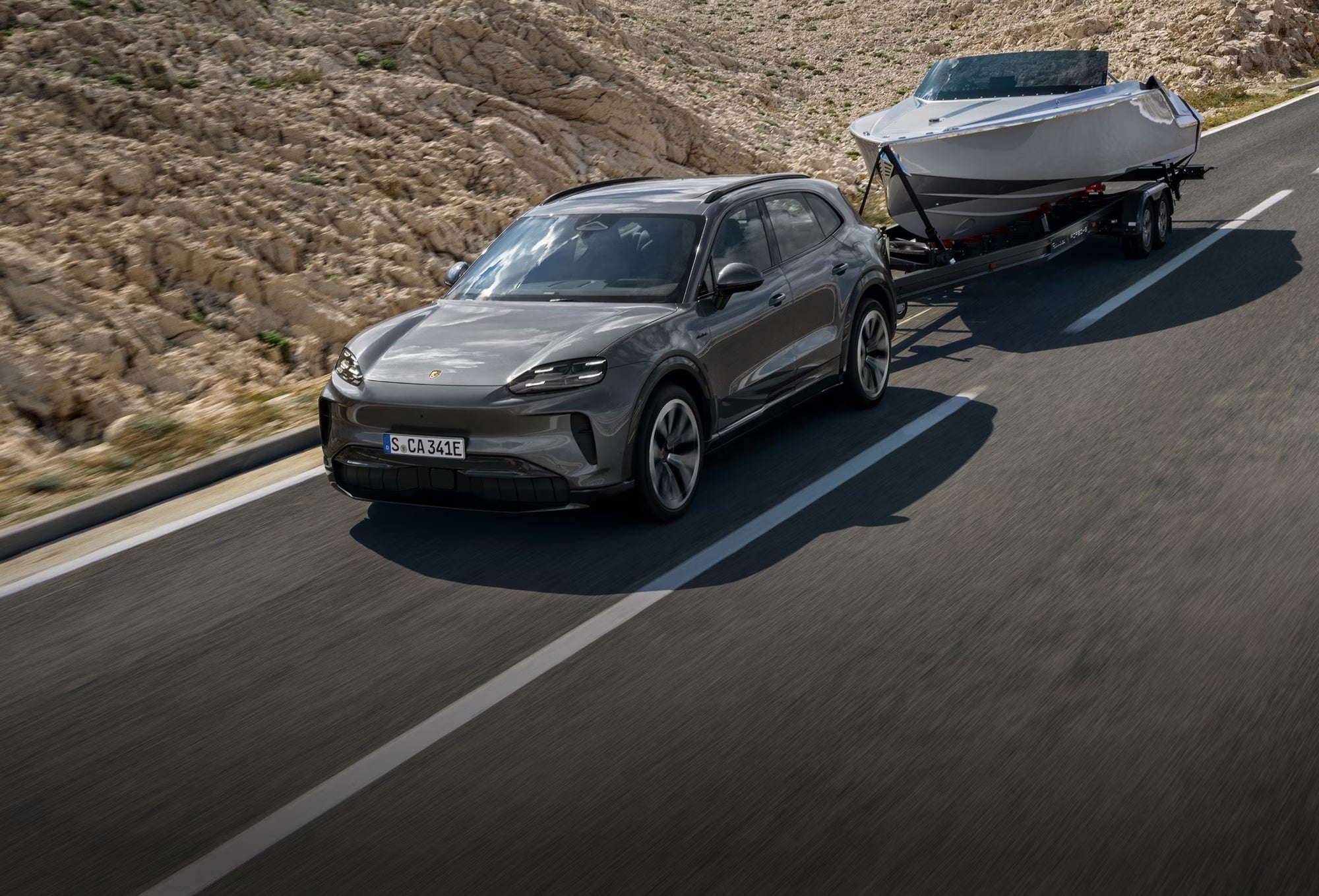 Porsche Cayenne towing a boat on the highway, showing why it remains the benchmark luxury performance SUV.