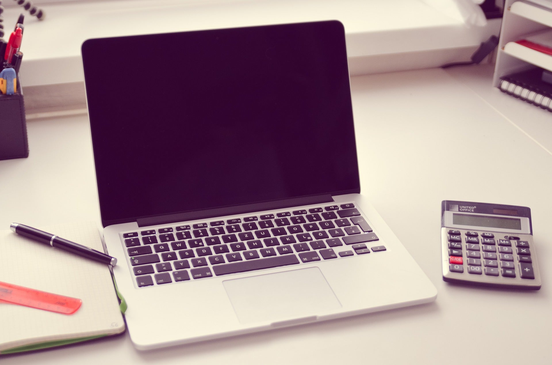 A notebook, laptop, and calculator all on a desk