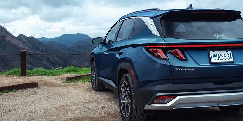 Blue Hyundai Tucson SUV parked near a mountain landscape viewpoint